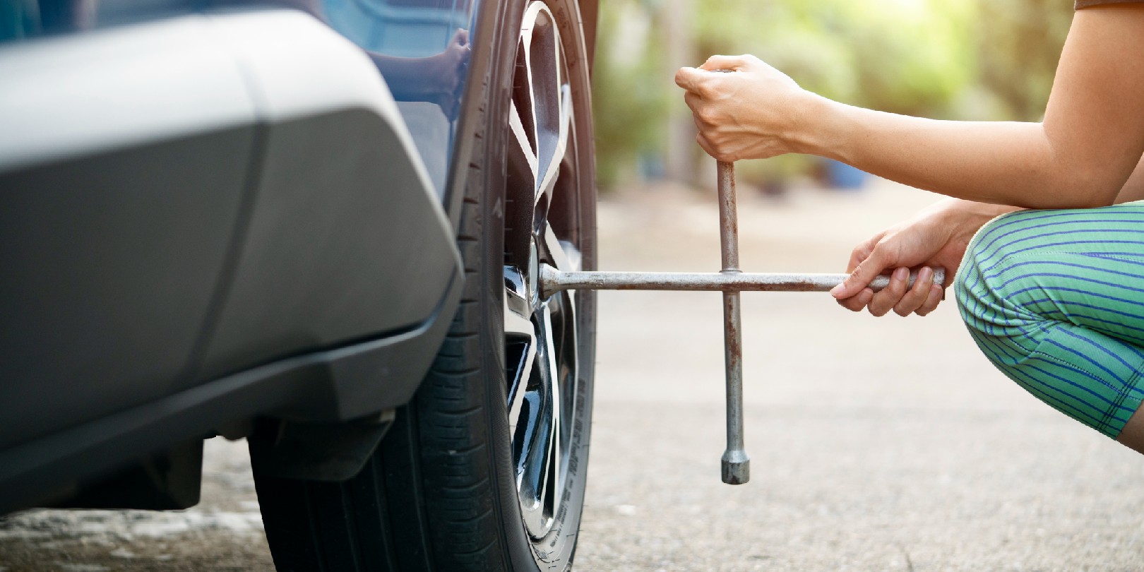 driving-on-a-spare-tire the-independence Woman driver with tyre iron changing wheel on a roadside