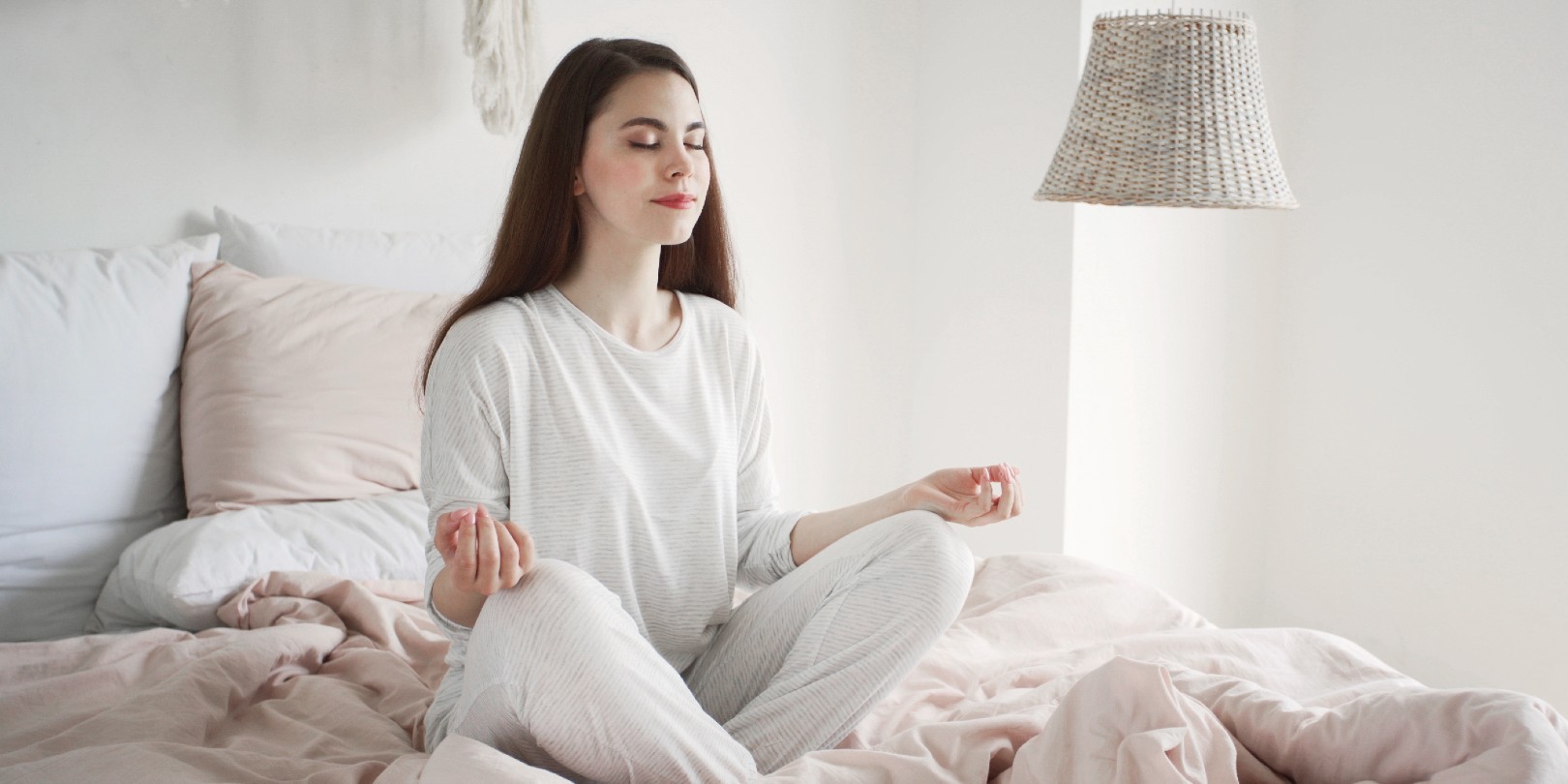 medication-before-bedtime the-independence Calm and dreamy young woman in pajamas sitting at meditation pose on bed in cozy bedroom