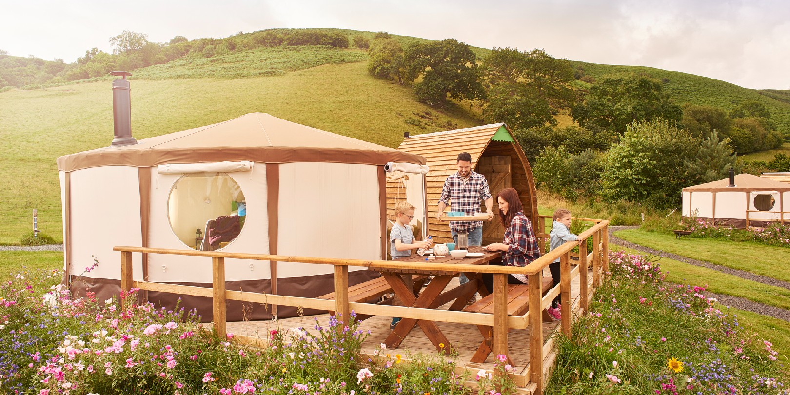 glamping-in-the-uk the-independence young family sit outside their yurt tent in wales