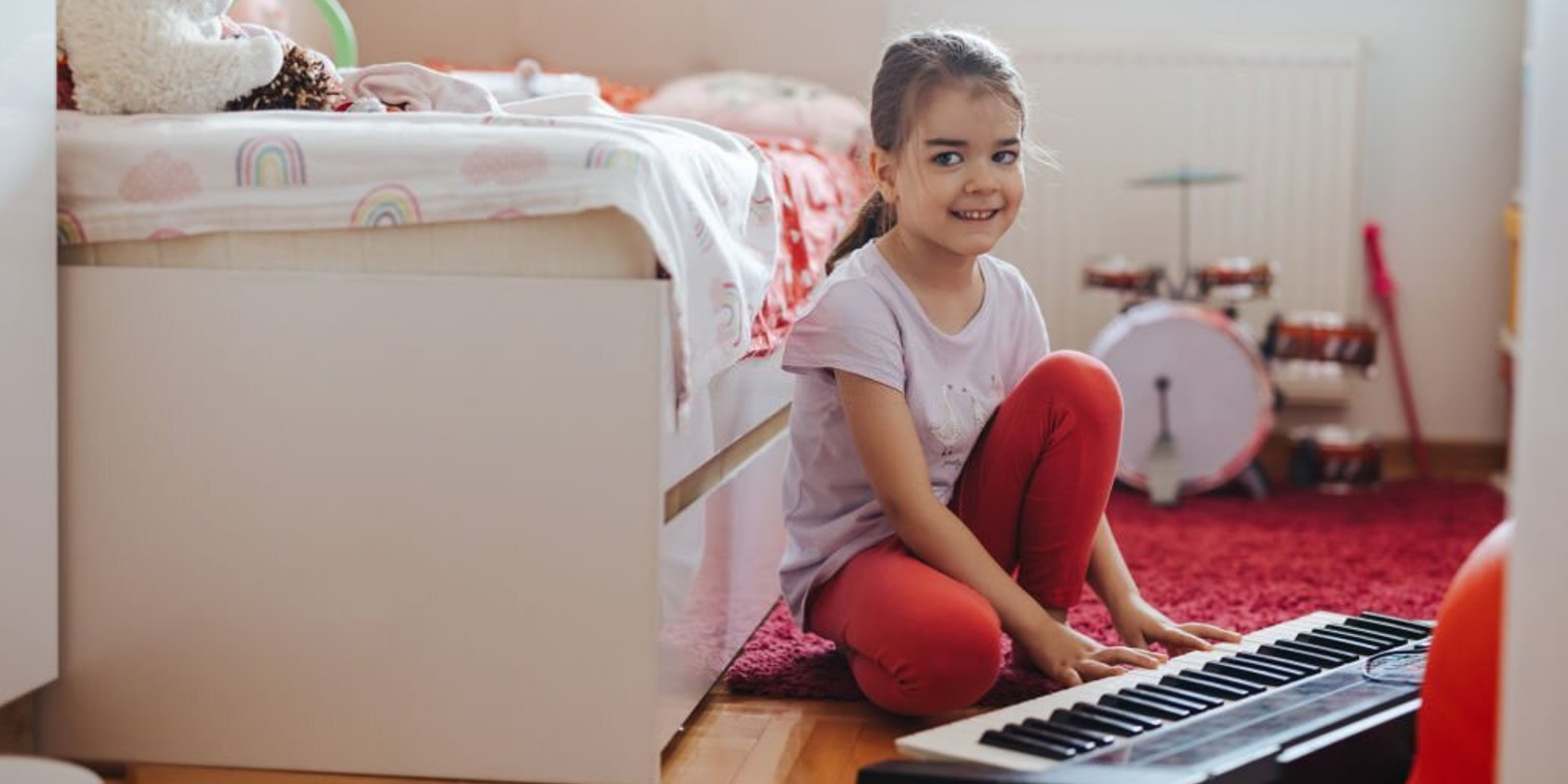 small-playroom-ideas the-independence Cute little girl sitting on floor in her playroom and playing synthesizer at home