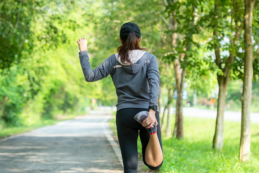 warm-up-running-theindependence Healthy woman warming up before jogging run and relax stretching her arms and looking away in the road outdoor